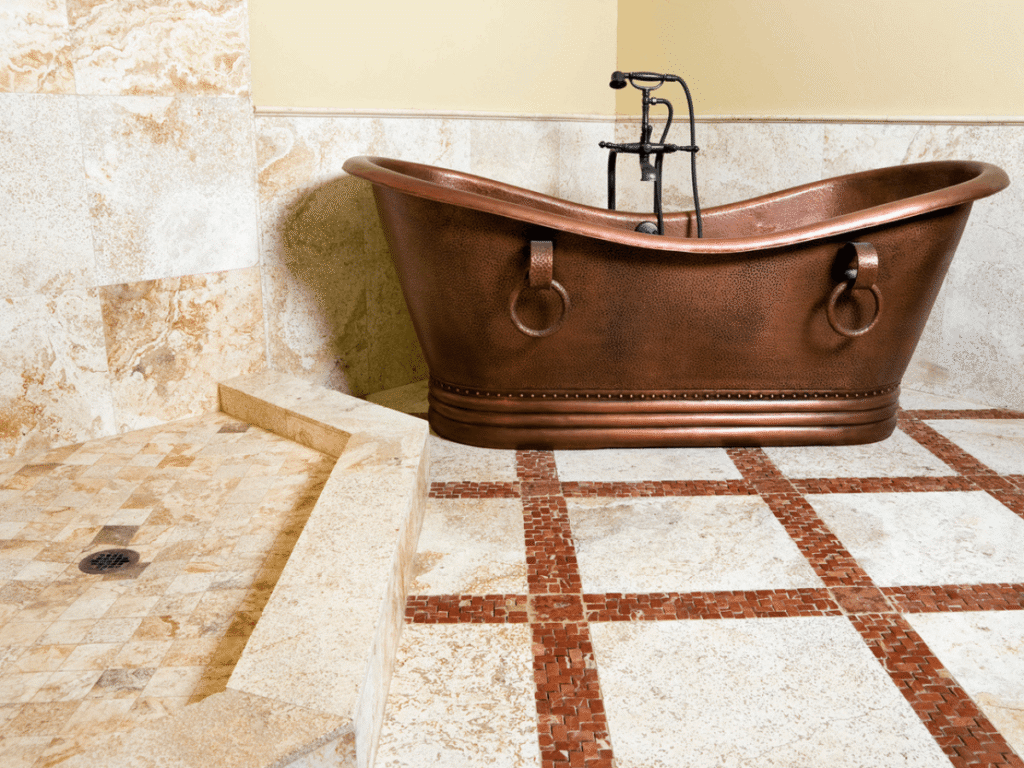 Rustic bathroom with hammered copper freestanding bathtub, stone tile flooring, and walk-in shower creating a warm, spa-like atmosphere.