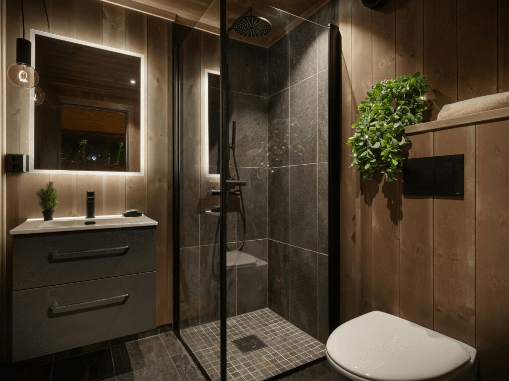 Contemporary bathroom with wood panel walls, glass walk-in shower, LED-lit mirror, floating vanity, and black fixtures creating a warm, modern design.
